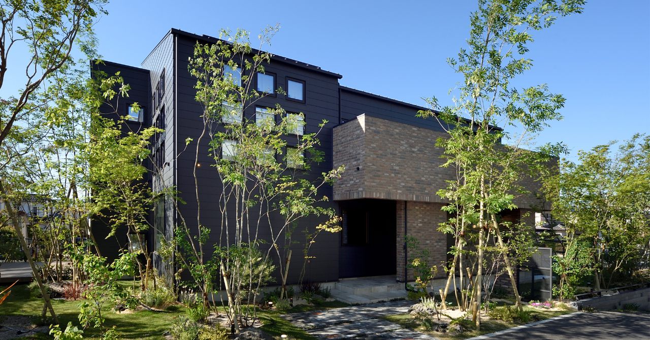 シンボルツリーと庭の緑に囲まれた、自然と調和する住宅の外観