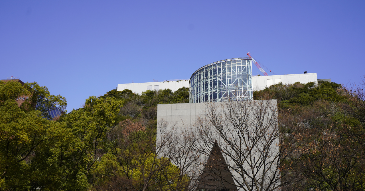 緑に覆われたステップガーデンと幾何学的な構造が印象的なアクロス福岡の外観