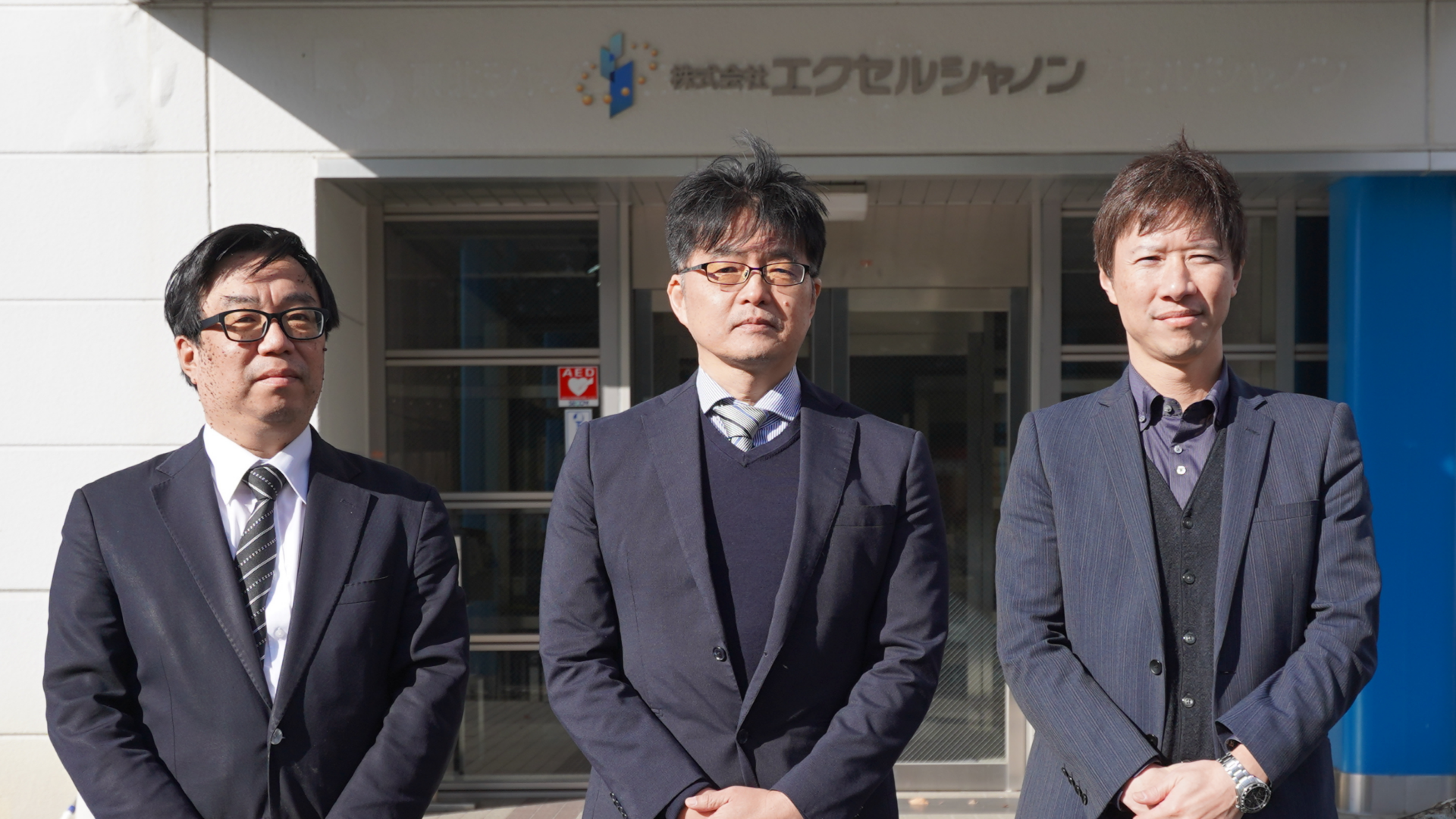 株式会社エクセルシャノンの開発・企画に携わる担当者が本社前に並ぶ様子