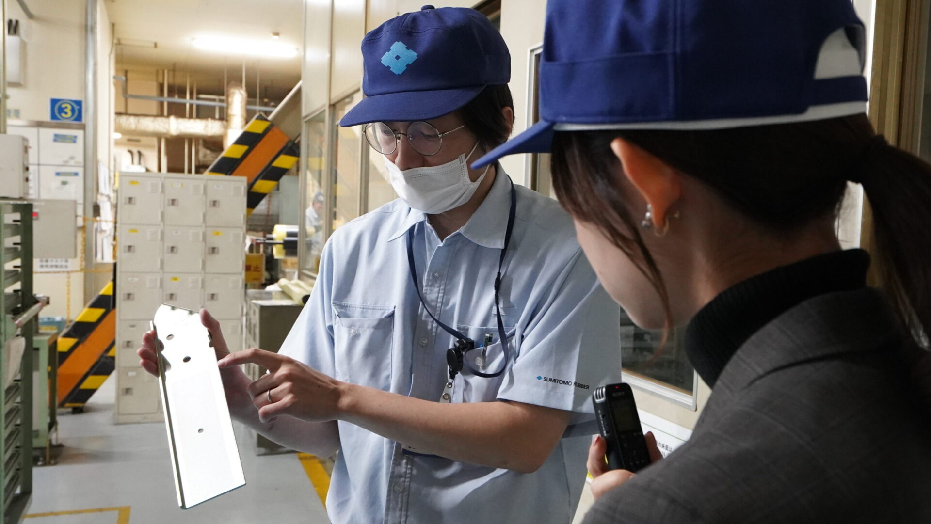 高減衰ゴムと金属部材を組み合わせる接着工程について説明を受ける工場見学の場面