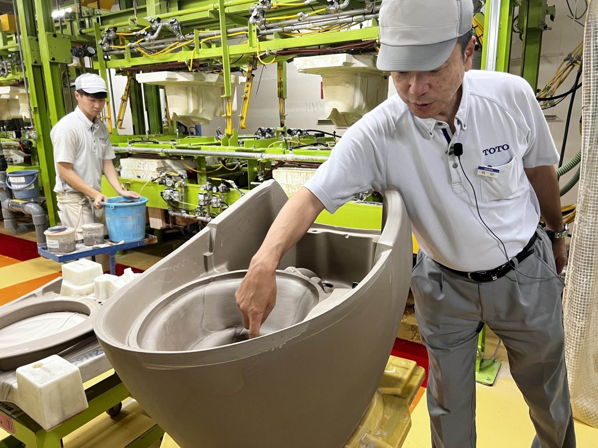 成形工程で作られた衛生陶器を前に、構造や工程を説明するTOTOの森田部長