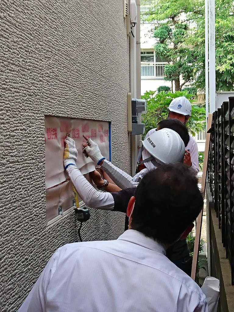 外壁の一部を開口し、断熱材の状態を確認する作業中の職人