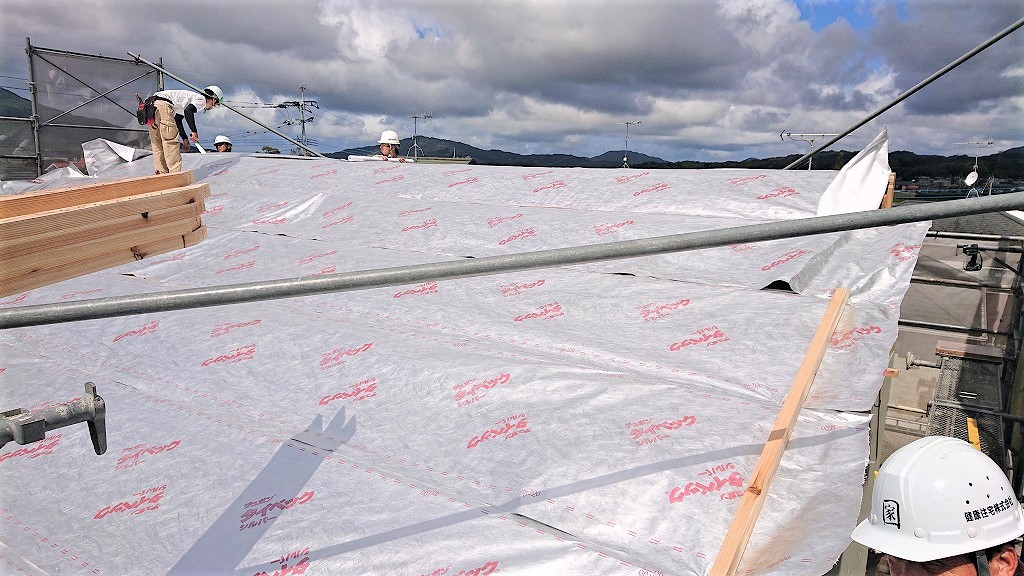 木造住宅の屋根全体に遮熱・透湿防水シート「タイベックシルバー」を敷設する作業風景