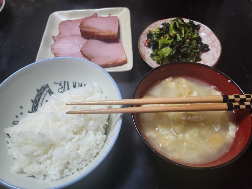 ごはん、味噌汁、ハム、いただいた高菜の漬物が並んだ日本の朝食