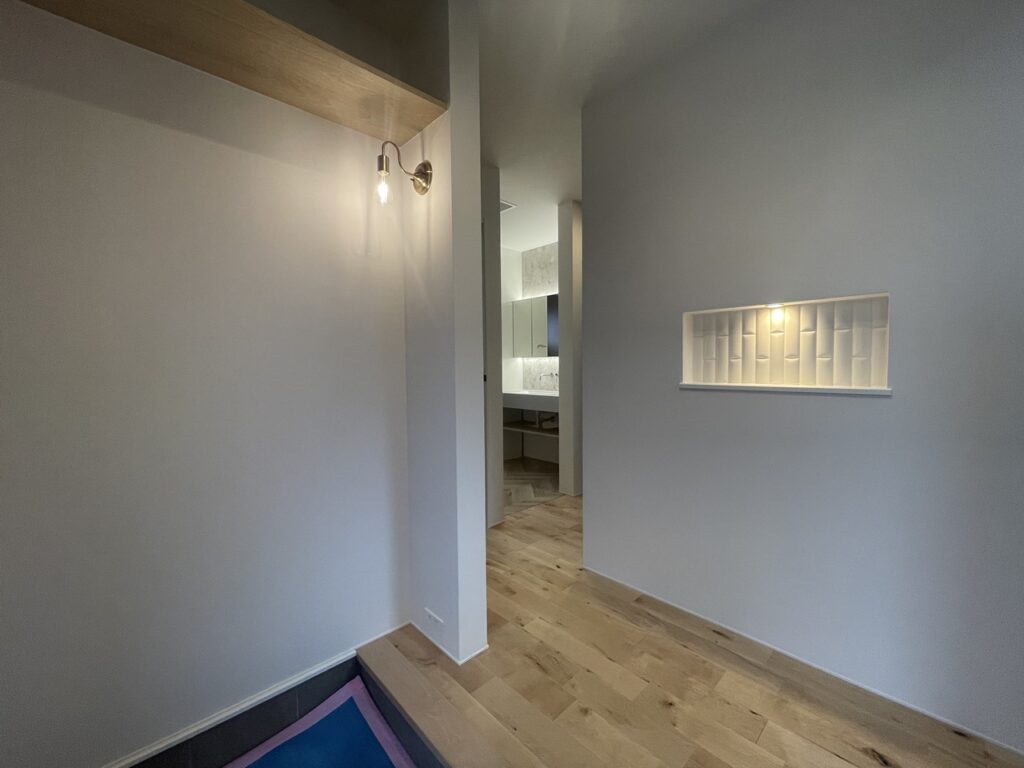 石調タイルの壁に取り付けられた間接照明付きの木製棚