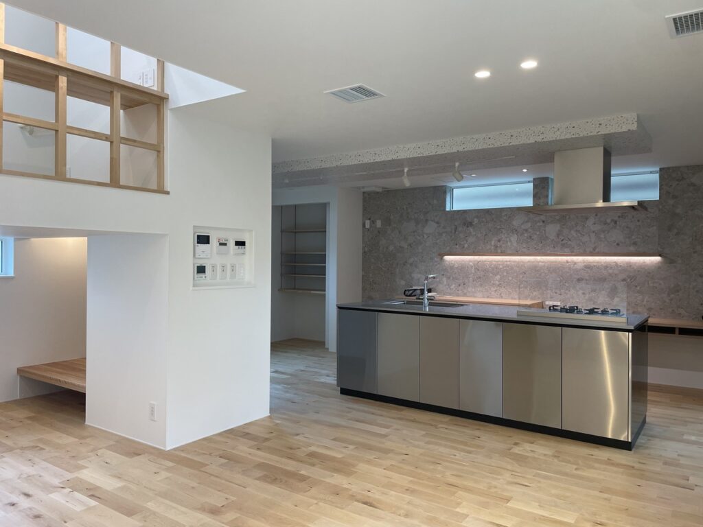 ステンレス製アイランドキッチンとフラメンタタイルの壁面が映えるLDKの全景