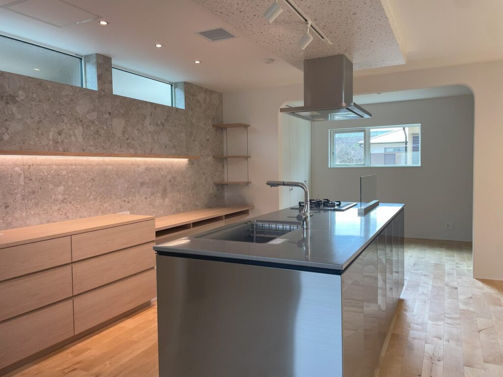 フラメンタタイルが貼られた壁と木製収納が調和する、アイランドキッチンの側面からの内観