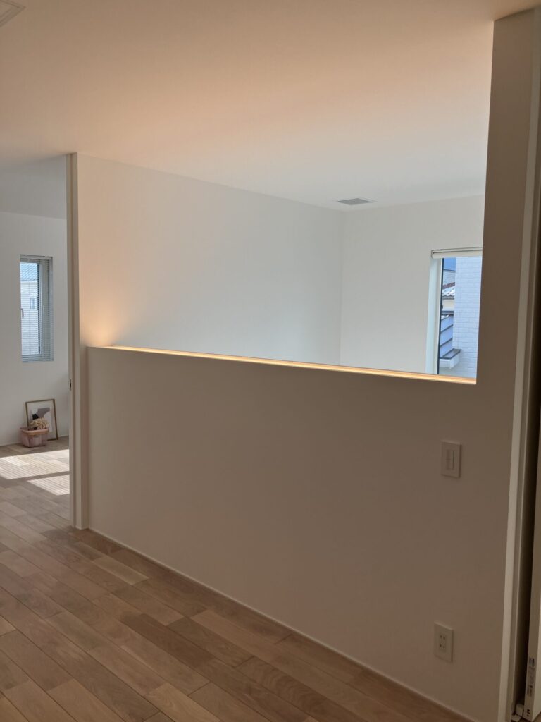 吹き抜けの腰壁に笠木を設けず、光のラインで奥行きを演出した内観