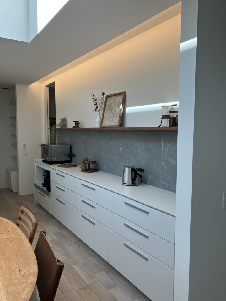 笠木を設けずコーブ照明を組み込んだ、線を感じさせないキッチン背面収納