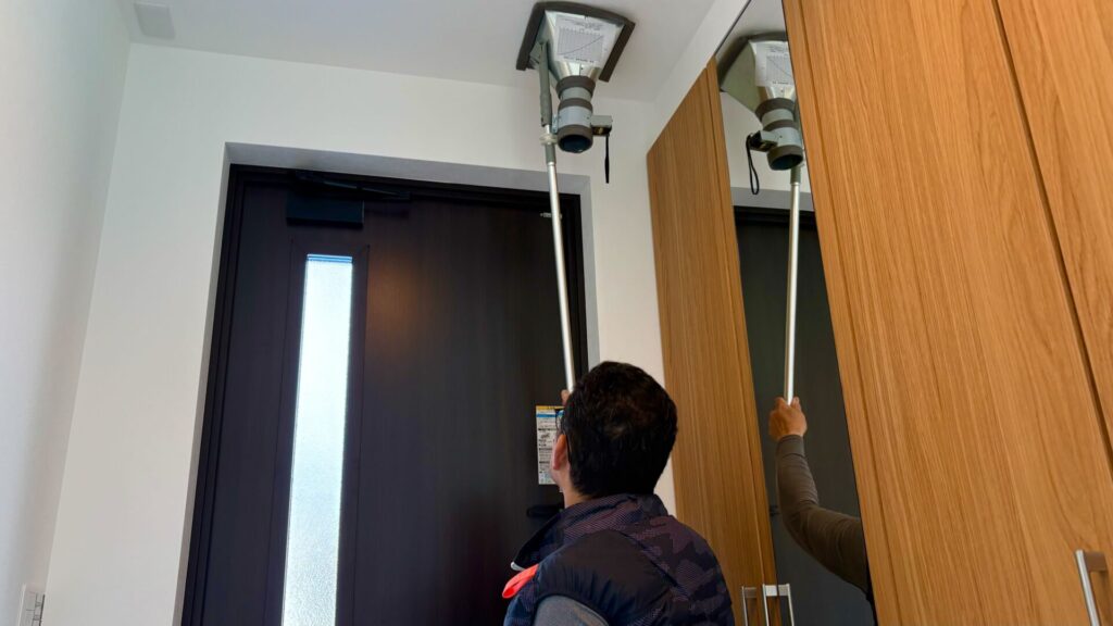 住宅の社内検査で、玄関付近の換気設備が正しく作動しているかを確認している様子