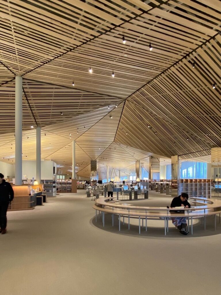 木製ルーバー天井の下に多様な読書席が広がる、開放感のある那須塩原市図書館「みるる」の内観