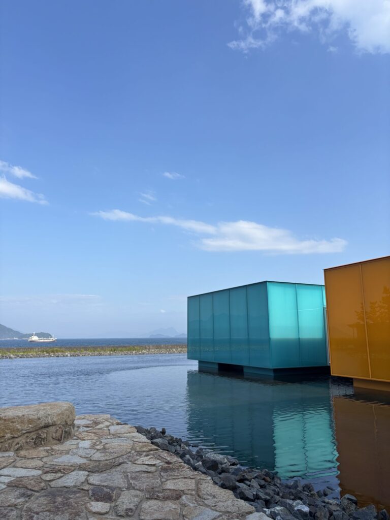 水盤に浮かぶカラフルな可動展示室が海と連続して見える美術館の外構