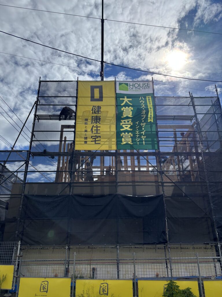 建て方工事中の住宅現場に掲げられた健康住宅の受賞バナーと足場の様子