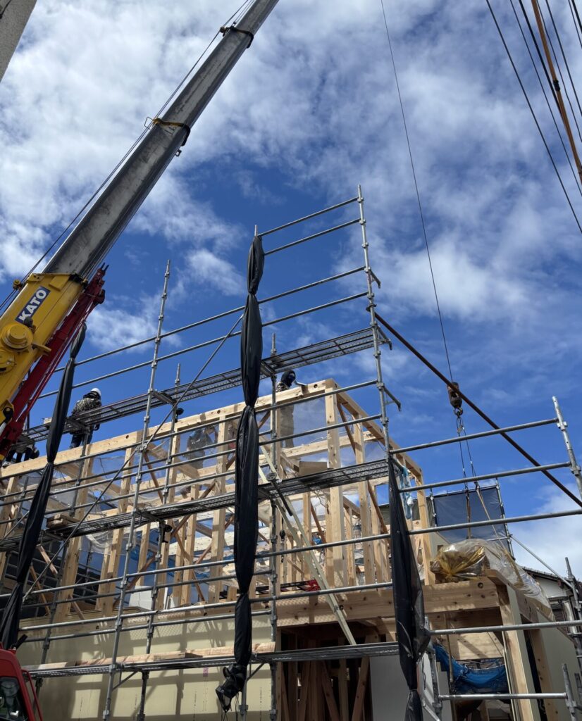 建て方工事でクレーンを使い木造住宅の骨組みを組み上げる現場の様子